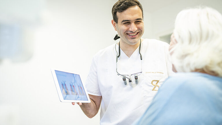 Zahnarzt zeigt Patientin Röntgenbild im Rahmen der Parodontologie-Behandlung